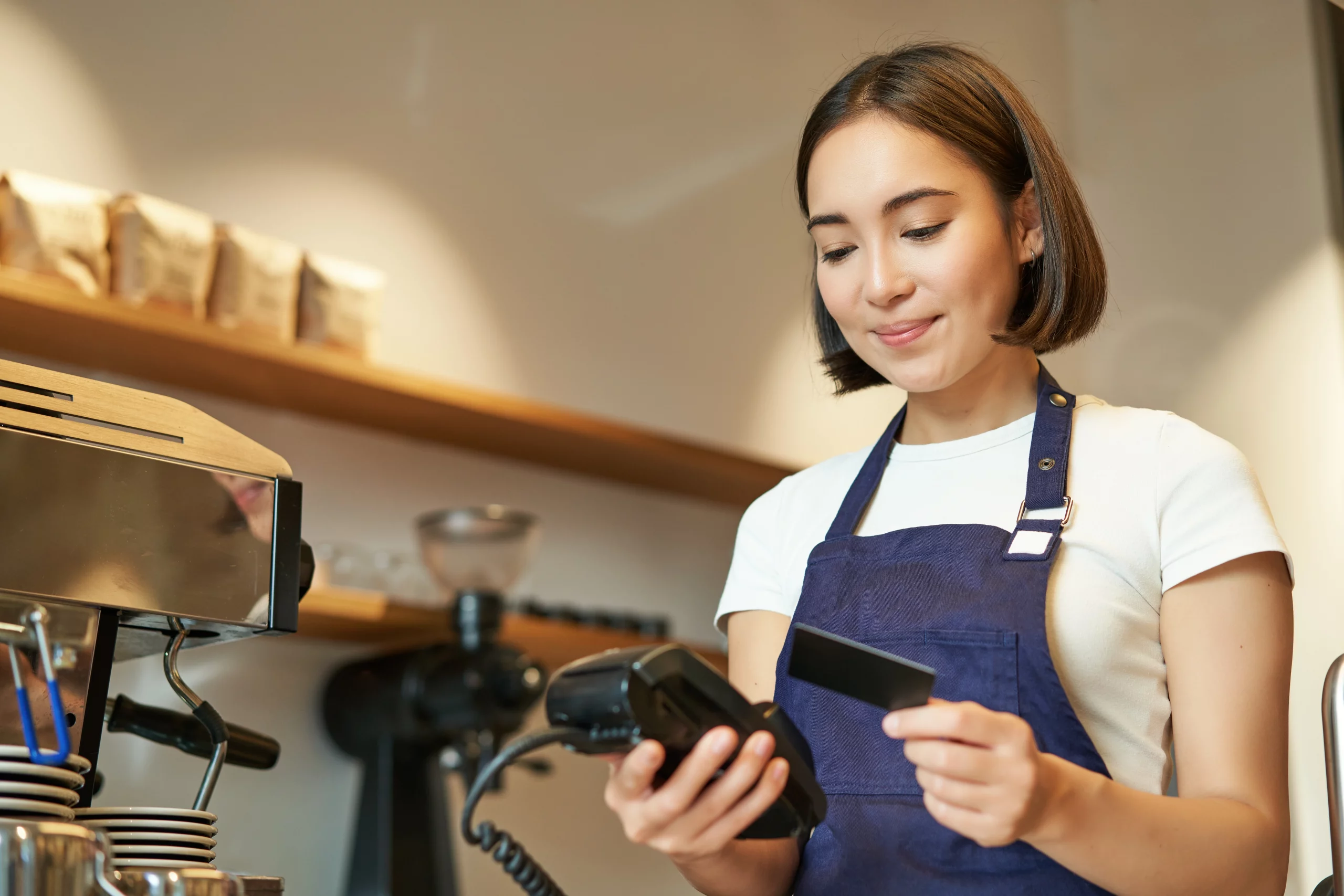 Female barista in a cafe processing a payment for a customer.